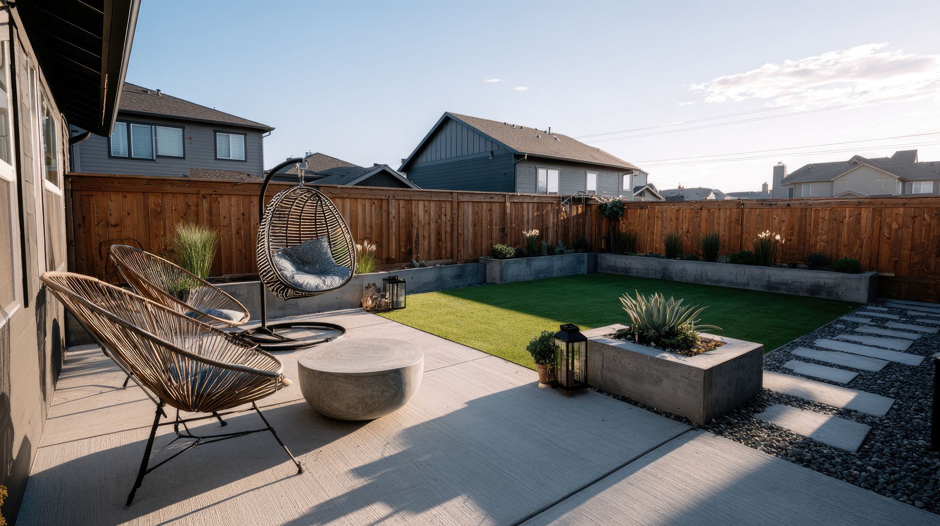 Modern backyard patio with seating, concrete features, and a grassy area.