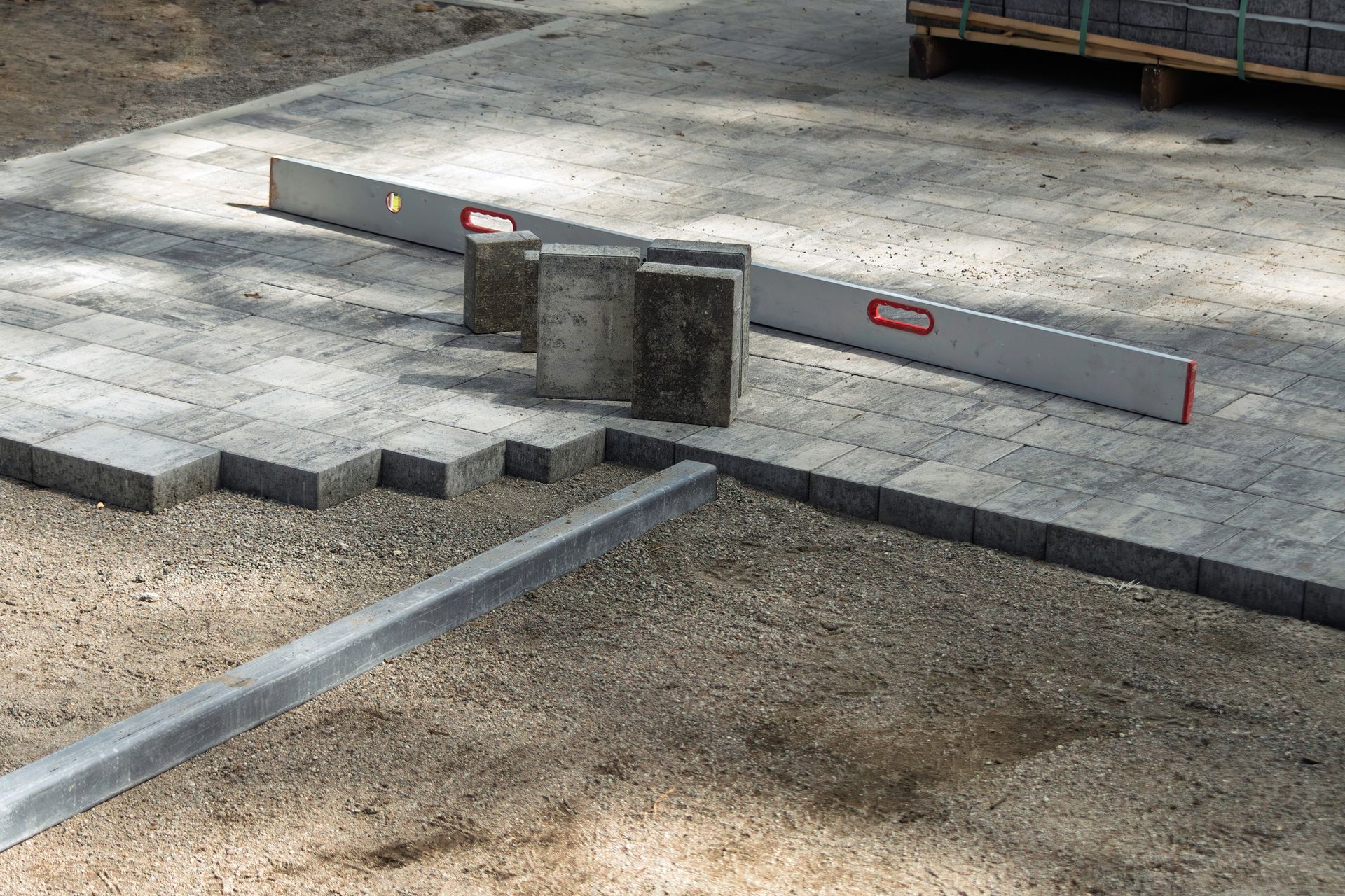 Gray retaining wall with steps, topped by a dense bed of green plants.