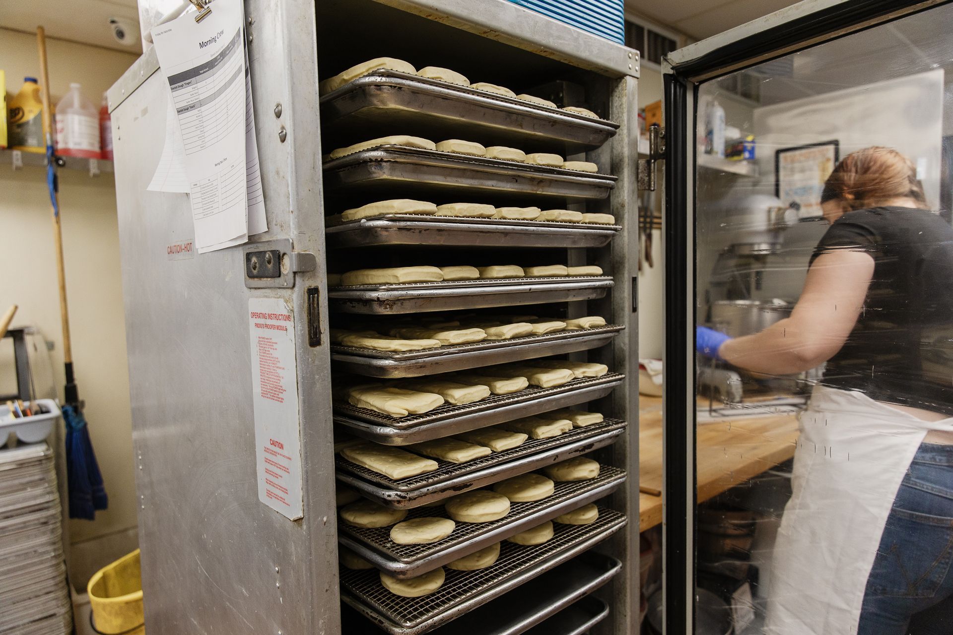 A square slice of white cake topped with piped white frosting, red and pink sprinkles, and a central red heart icing.