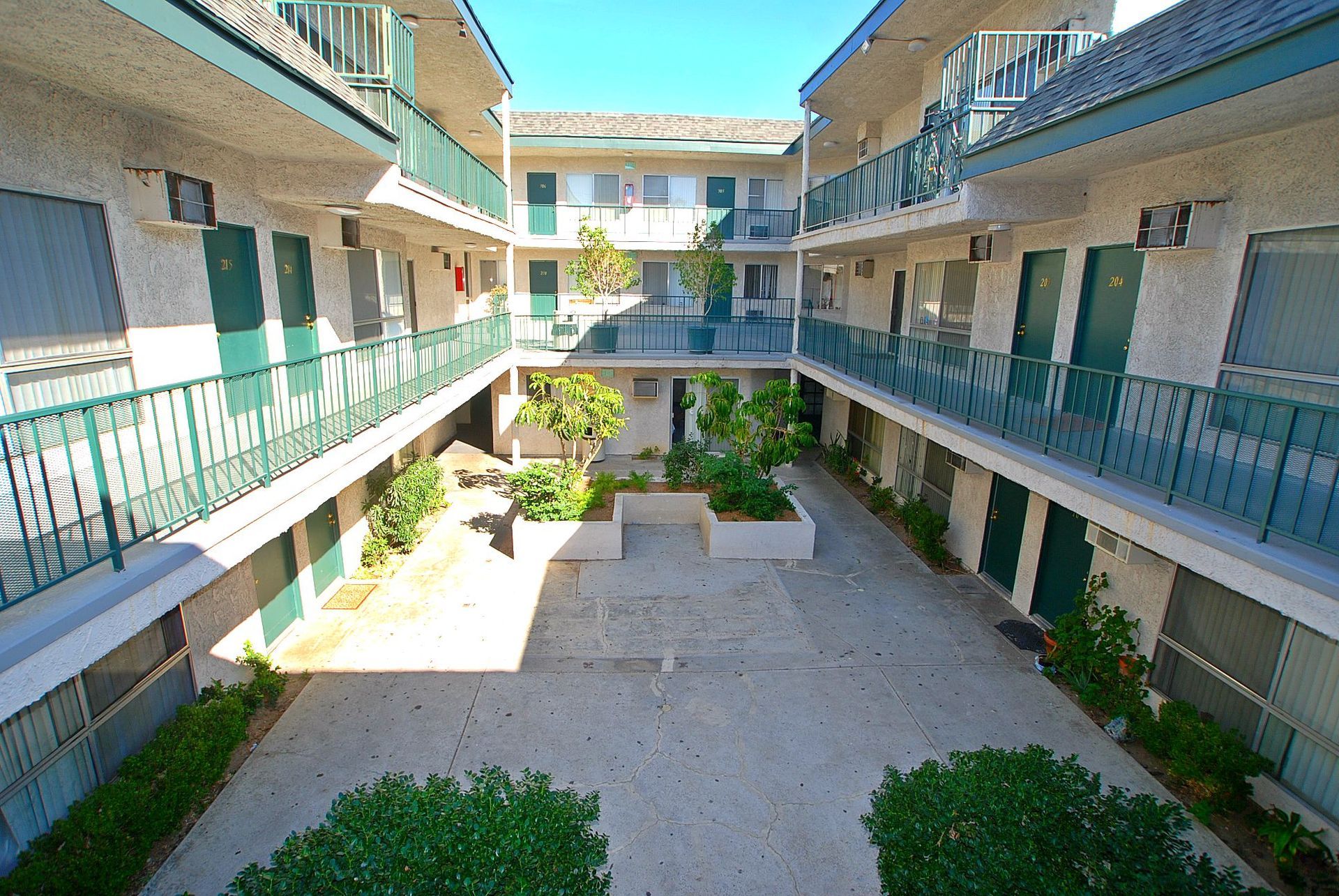 Courtyard apartment complex with multiple levels, green doors, and balconies.