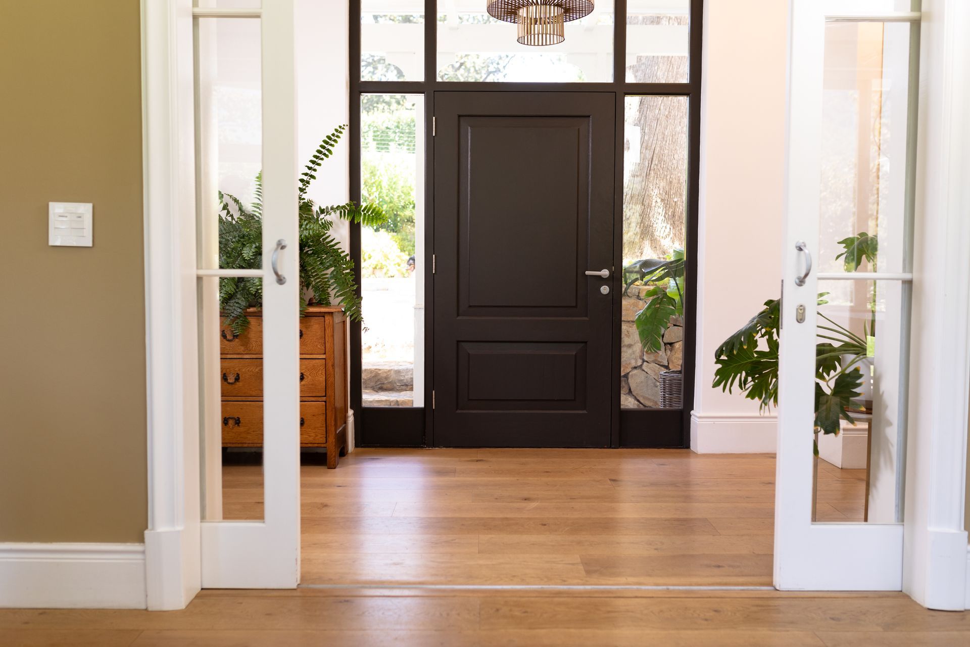 A hallway with a black door and white sliding glass doors leading to it.