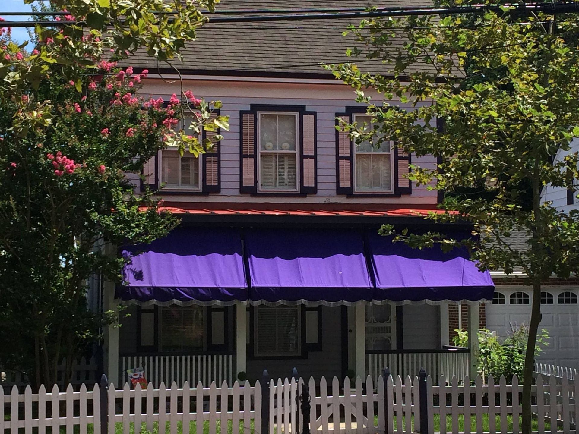 A house with a purple awning and a white picket fence