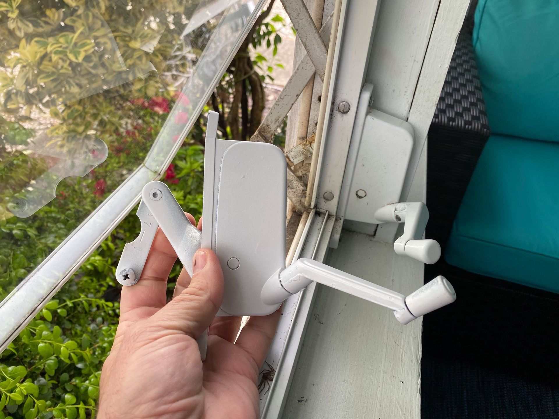 A person is holding a white device in their hand in front of a window.