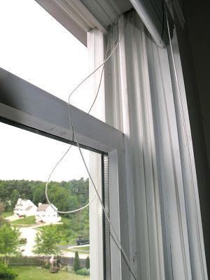 A window with white curtains and a cord hanging from it
