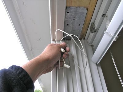 A person is pulling a cord on a window blind.