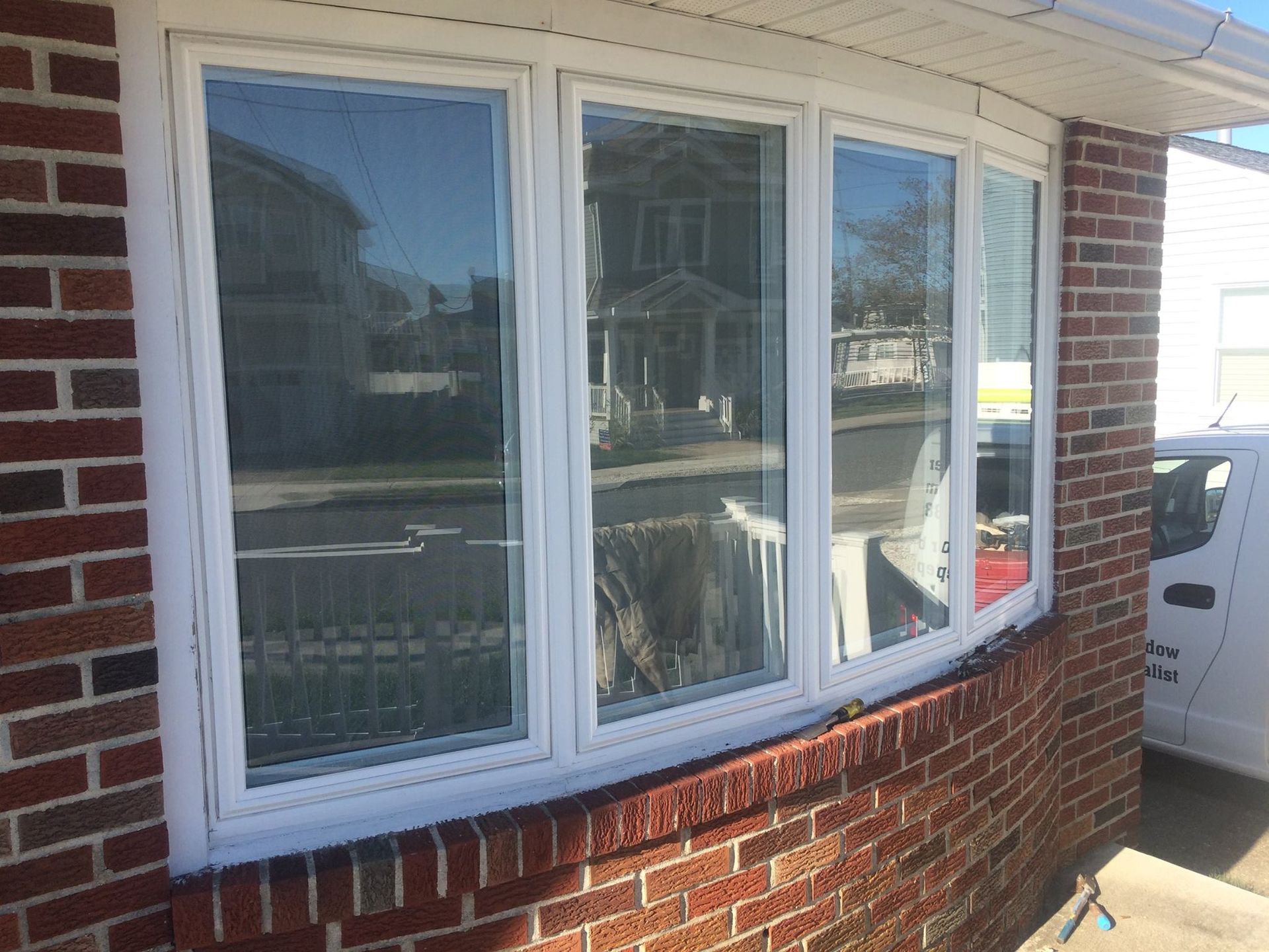 A white window is on the side of a brick building.
