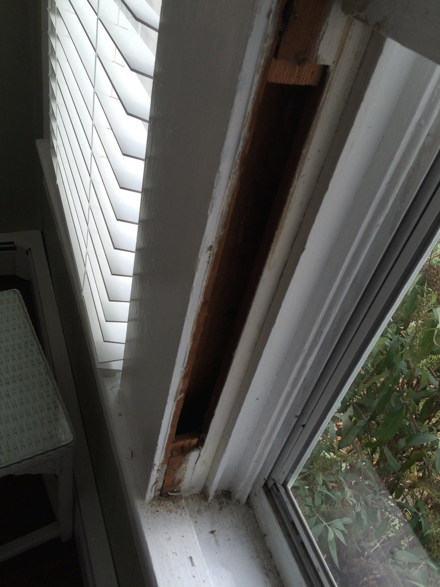 A window with blinds on it and a hole in it.