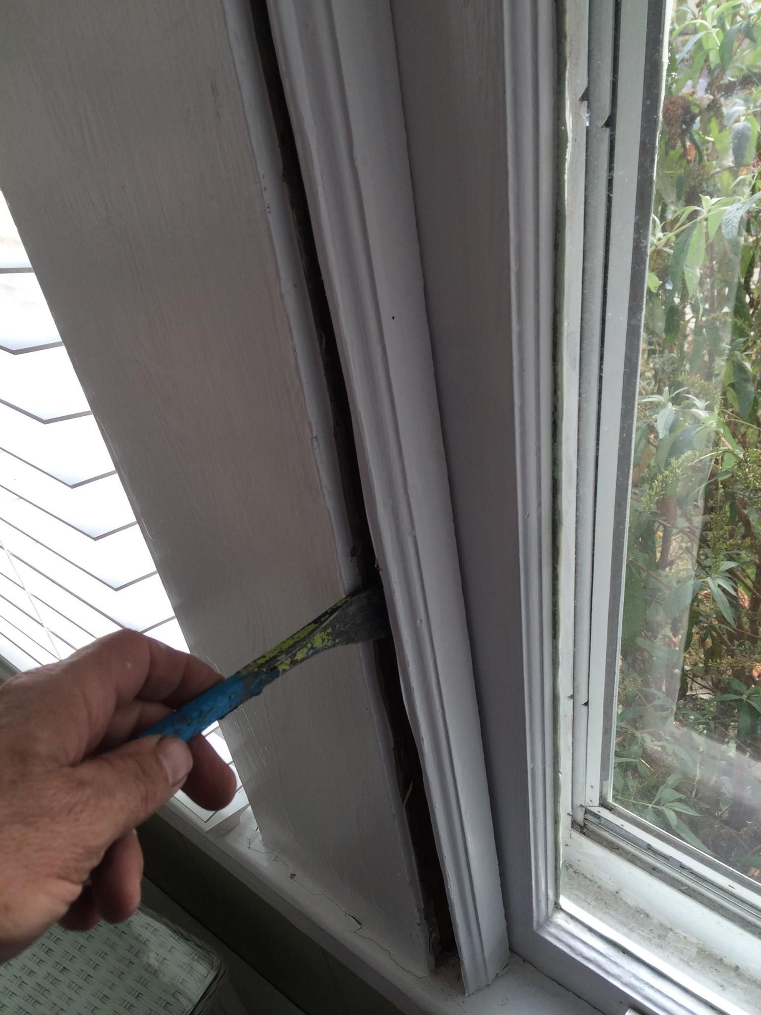 A person is measuring a window frame with a tape measure.