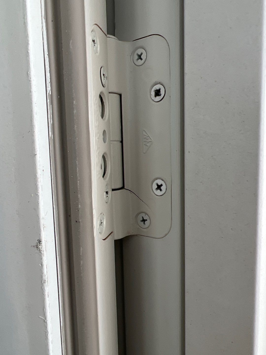 A close up of a white door hinge on a white door.
