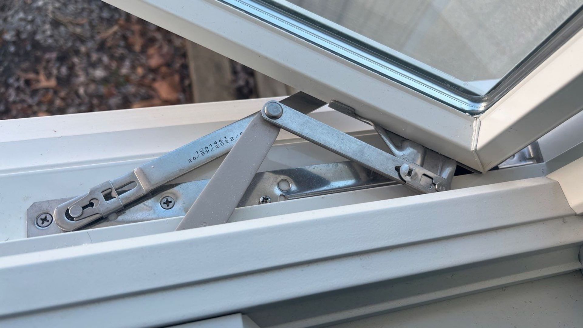 A close up of a window with a metal hinge on it.