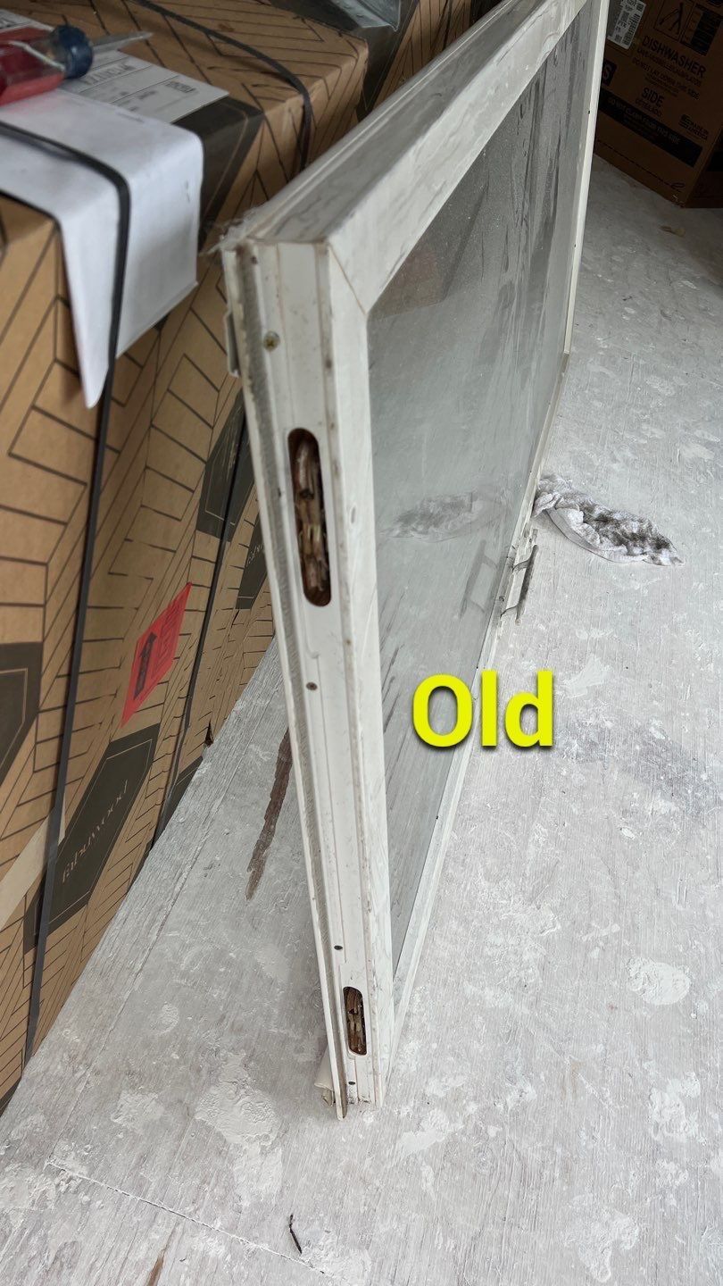 An old window is sitting on the floor next to a pile of cardboard boxes.