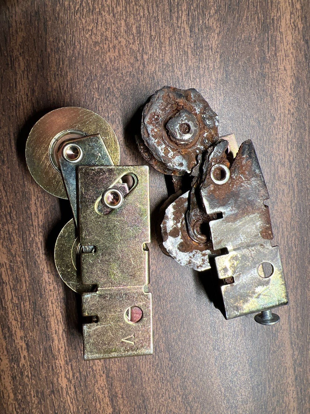 Two rusty metal parts are sitting on a wooden table.