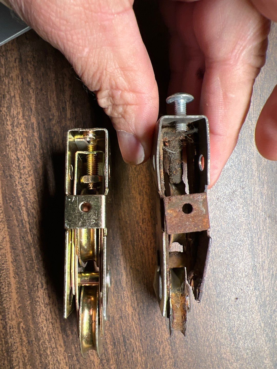 A person is holding two sliding glass door rollers in their hands.