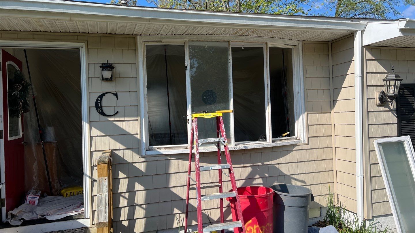 A ladder is sitting in front of a house with a broken window.