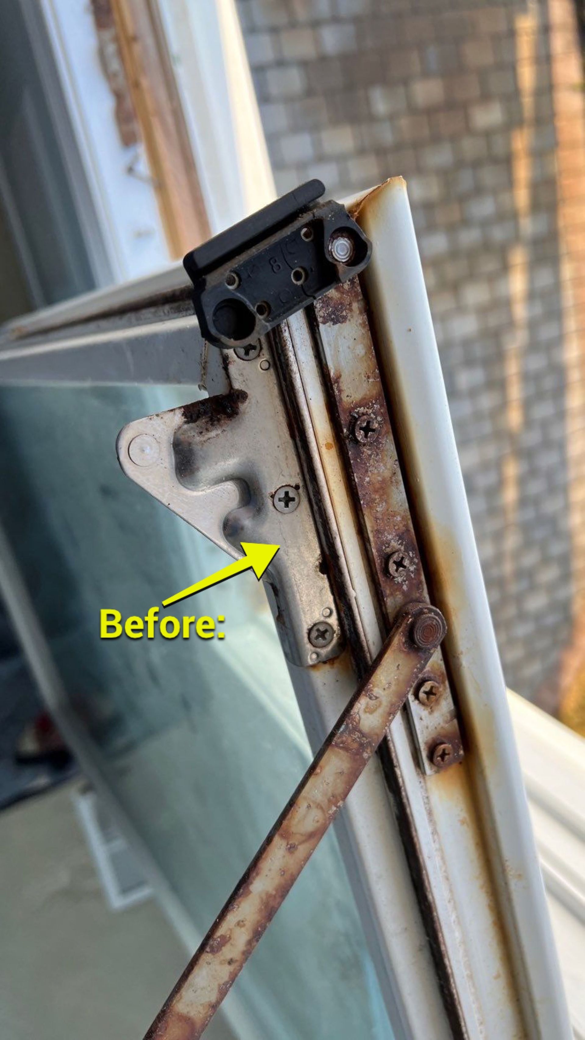 A close up of a rusty window with a yellow arrow pointing to it.