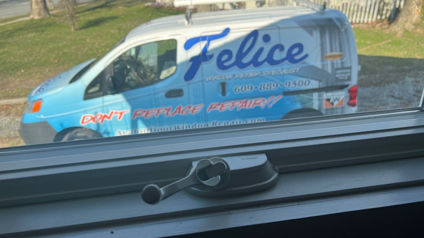 A blue van with the word felice on the side is parked in front of a window.