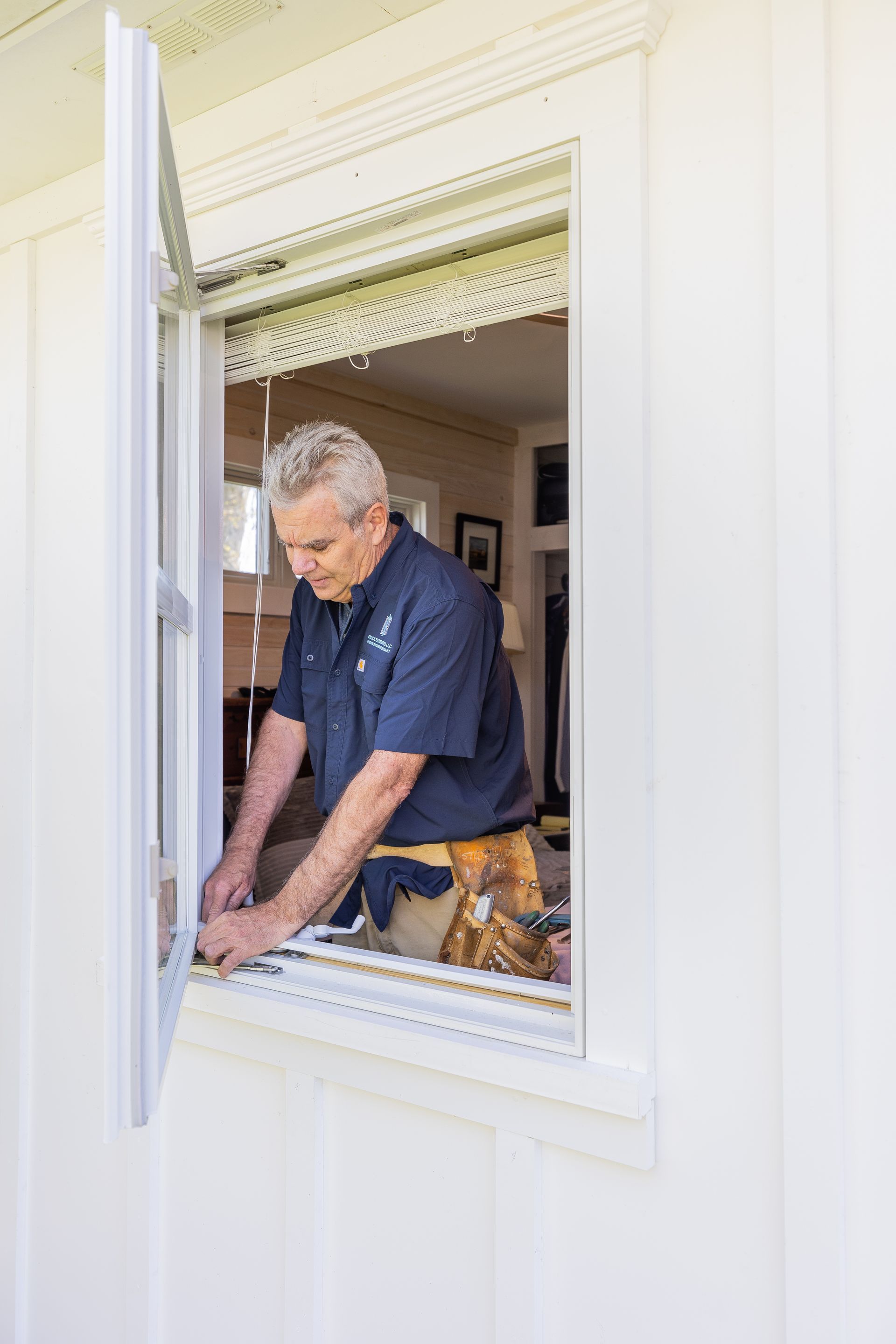 A man is installing a window in a house.