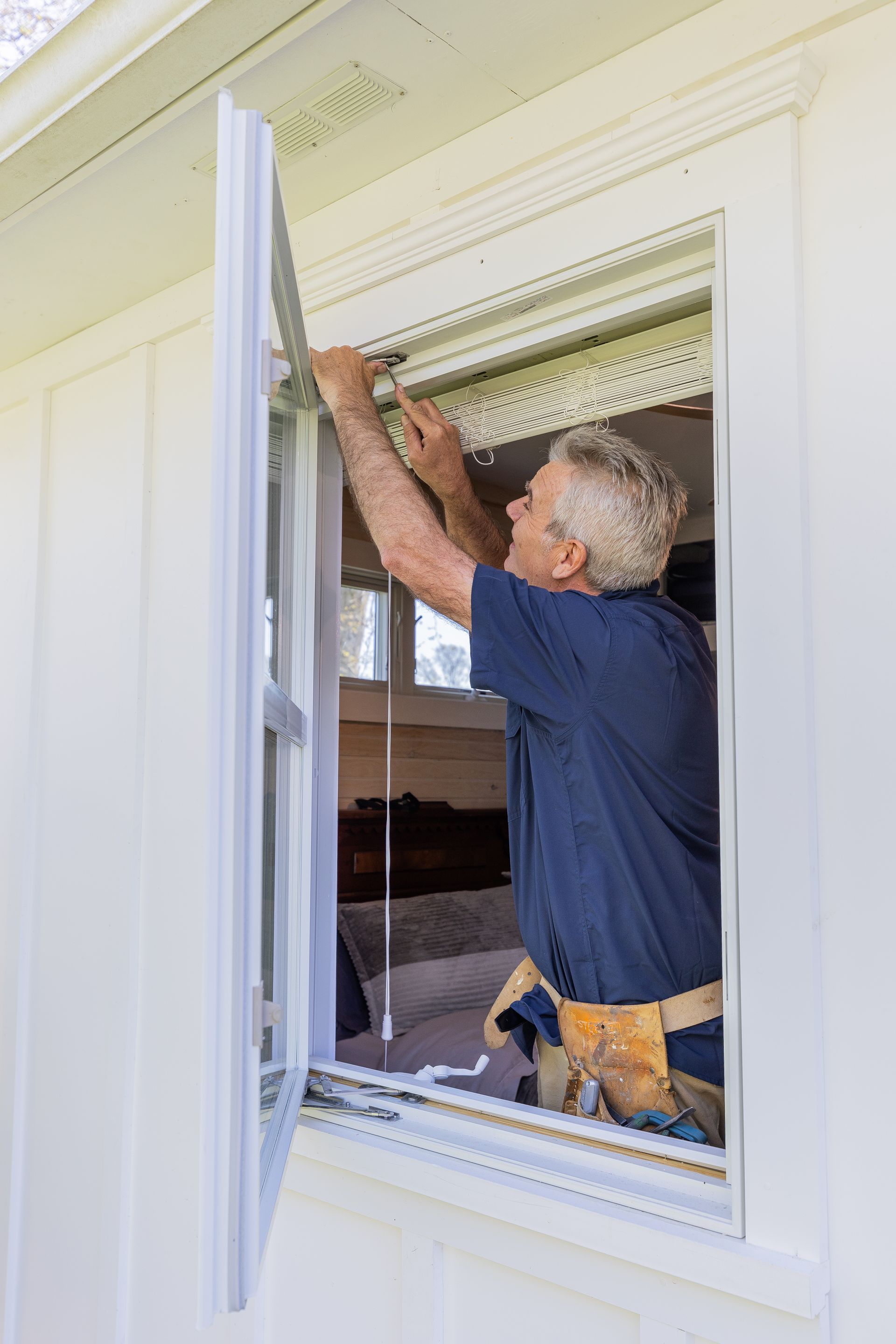 A man is installing a window on the side of a house.