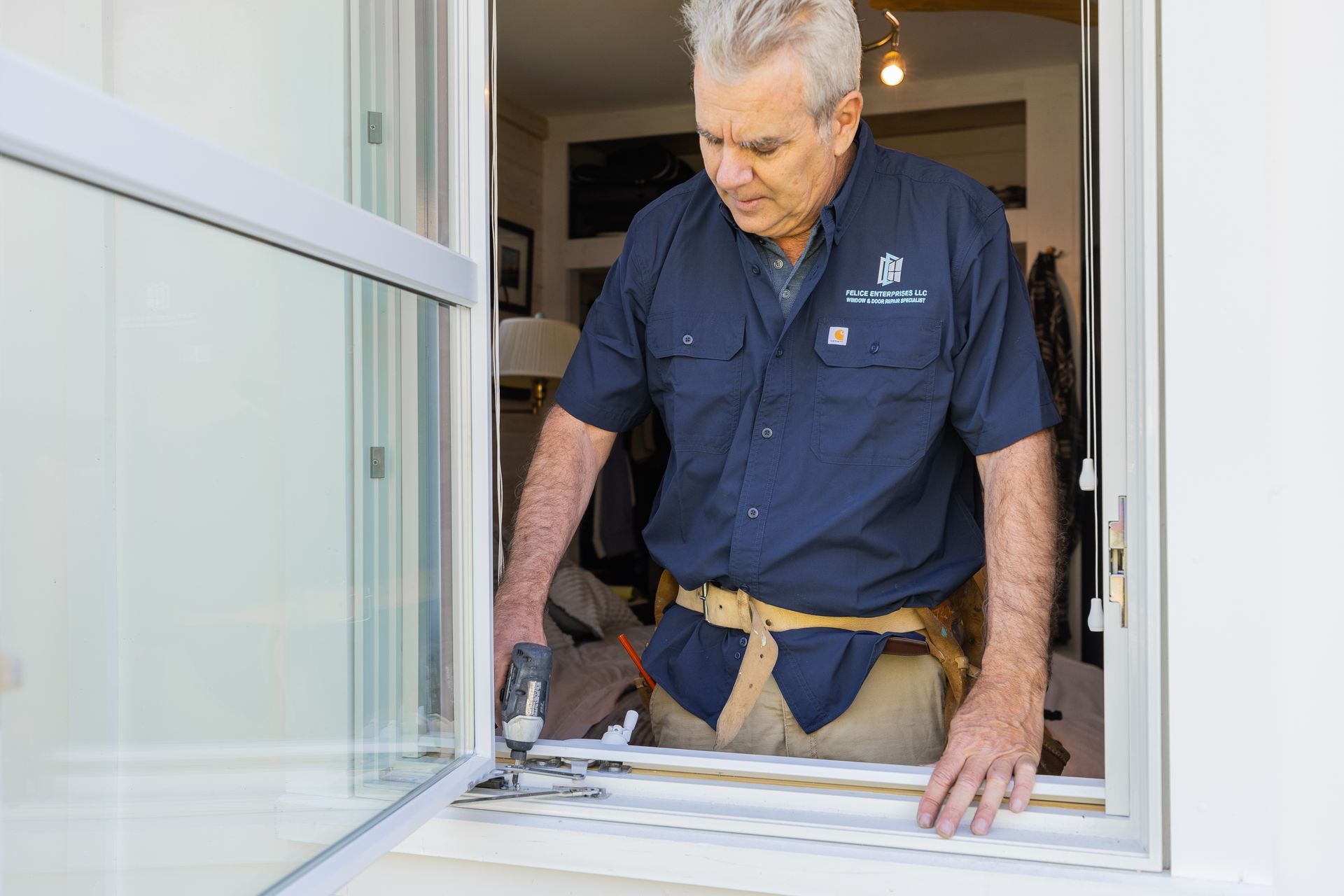 A man in a blue shirt is working on a window.