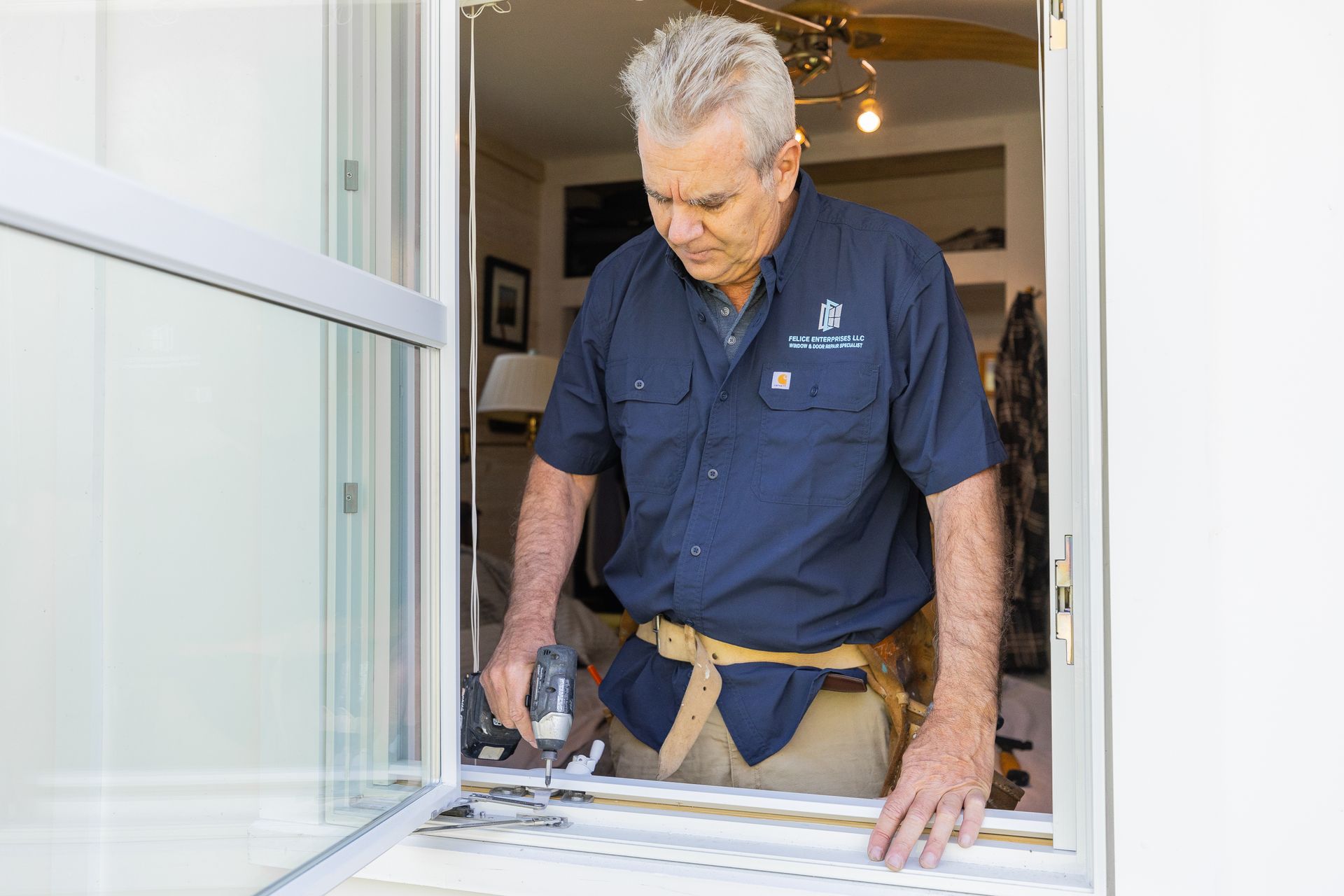 A man in a blue shirt is working on a window.