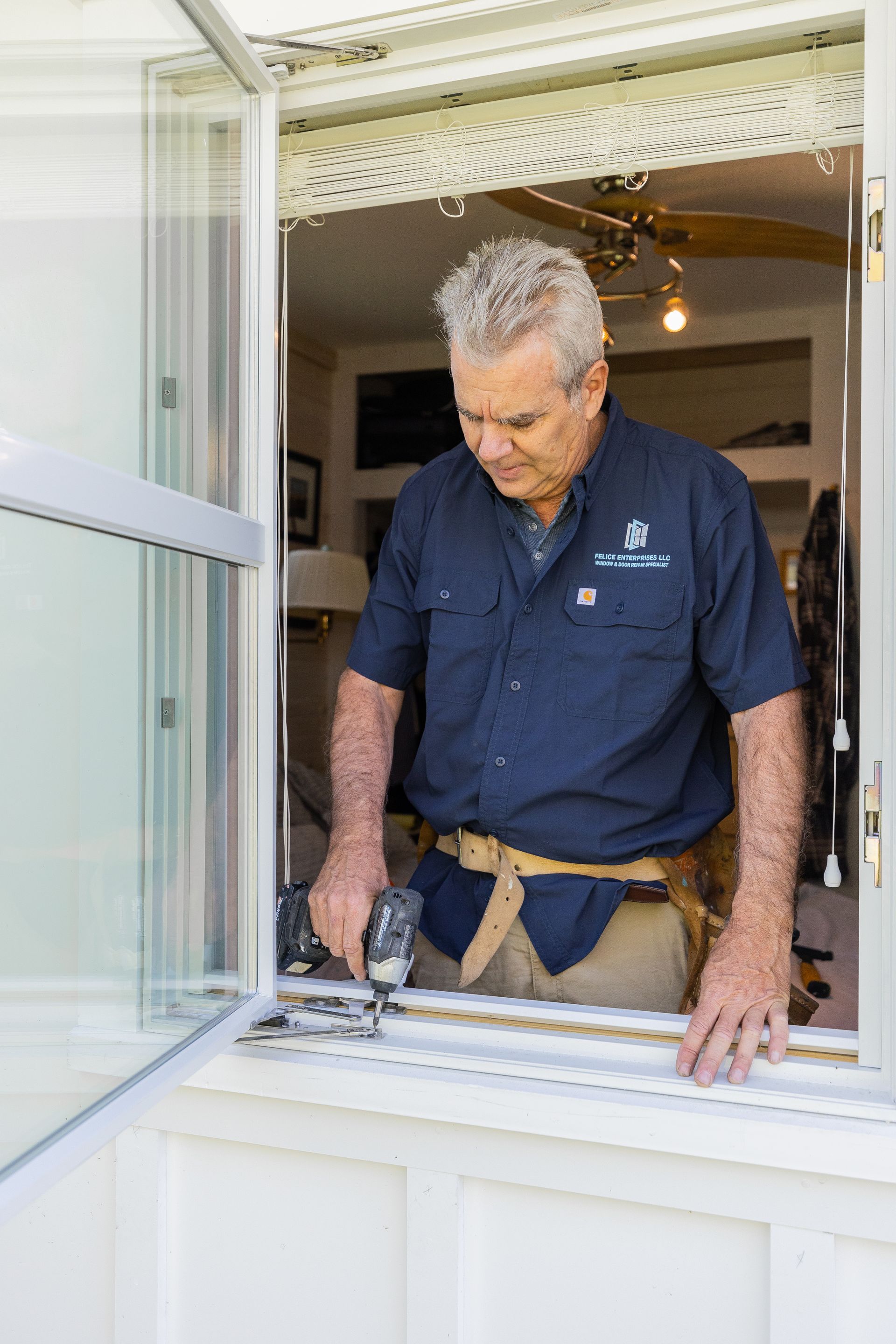 A man is working on a window with a drill.