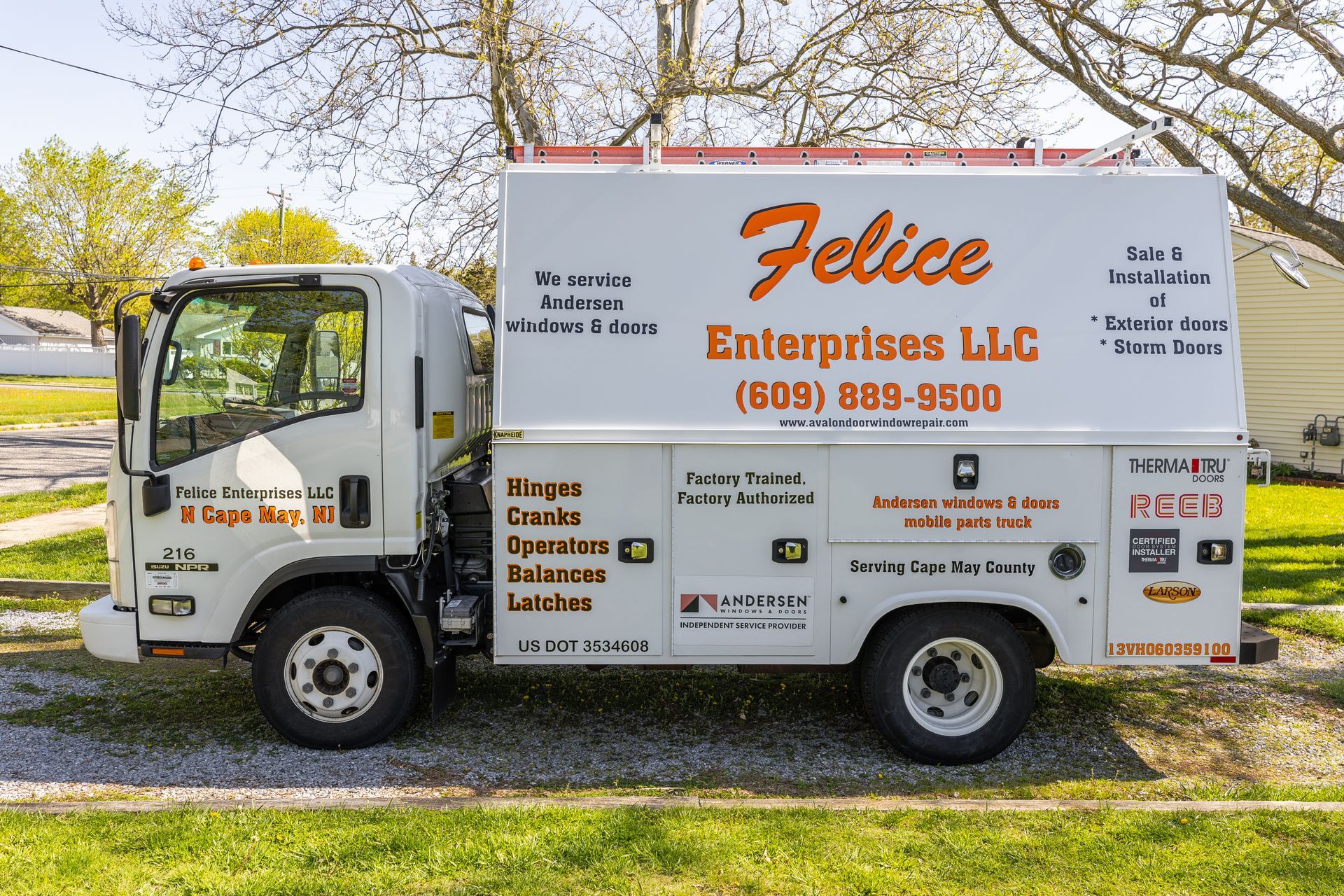 A white truck with the word felice on the side is parked in a grassy area.