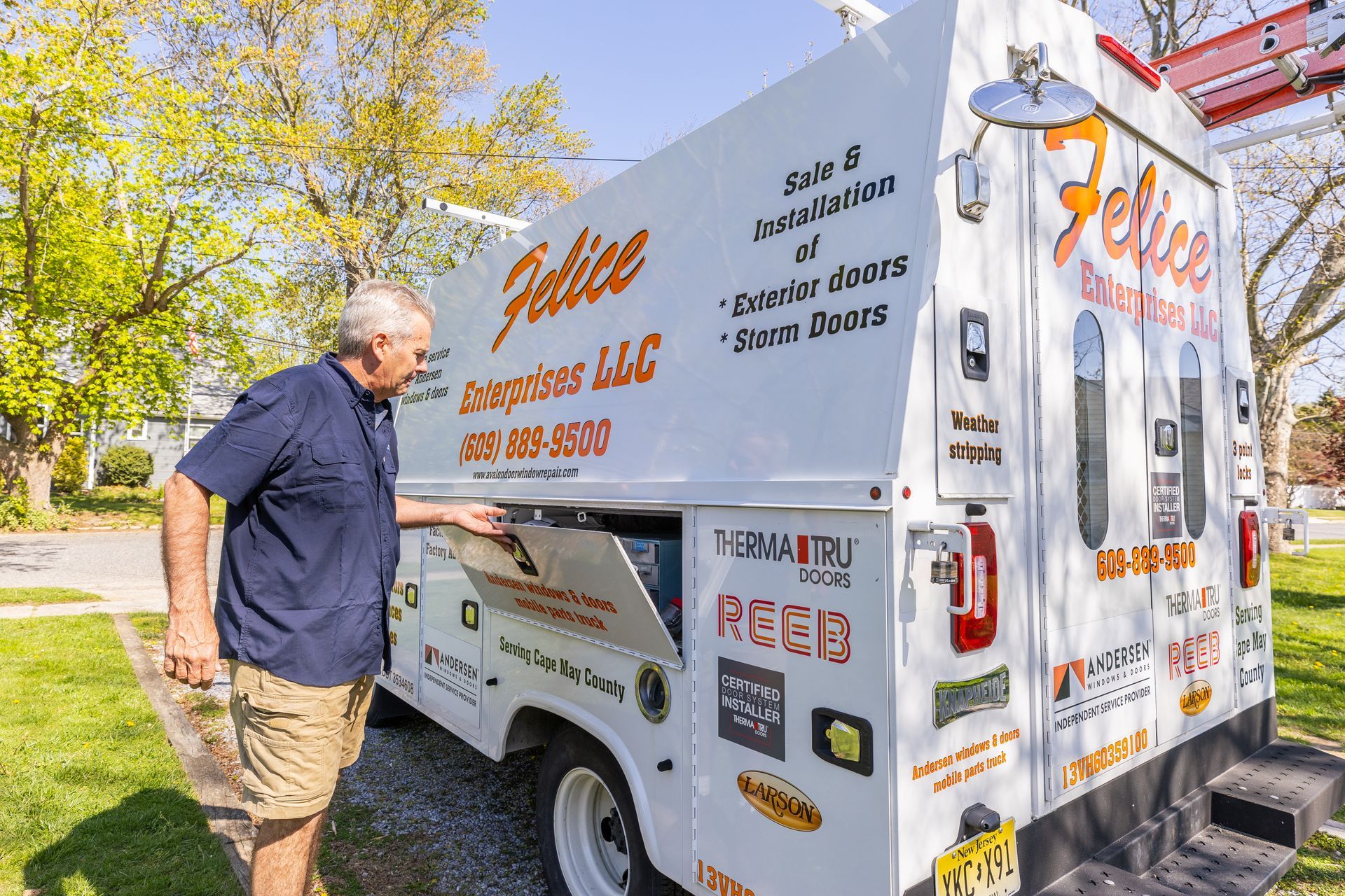 A man is standing in front of a white food truck.