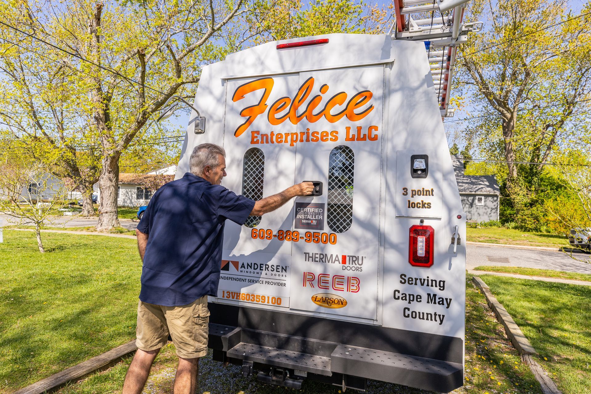 A man is pointing at a sign on the back of a truck.