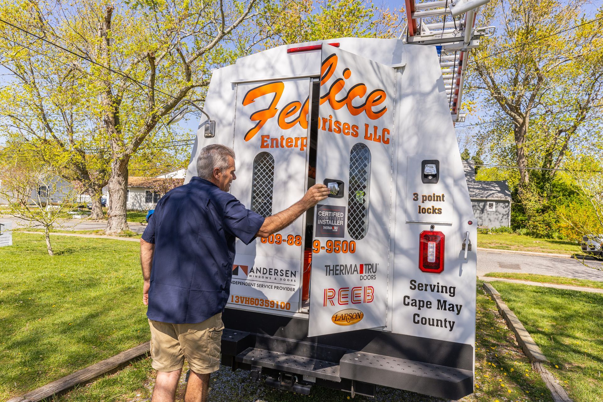 A man is opening the back door of a white truck.