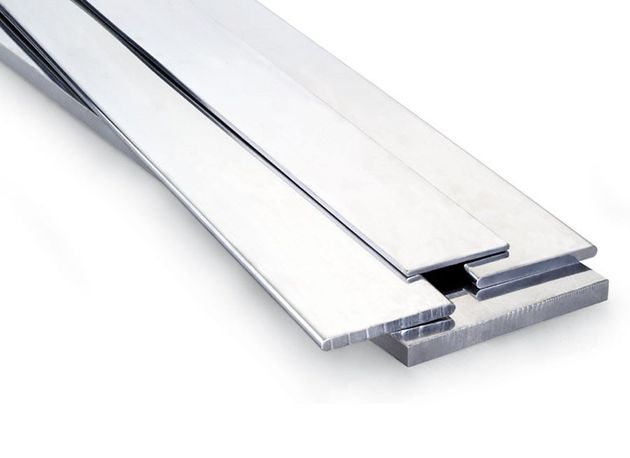 Primer plano de una tira de transición metálica en forma de T, de color plateado, que se utiliza para unir dos superficies de suelo diferentes.