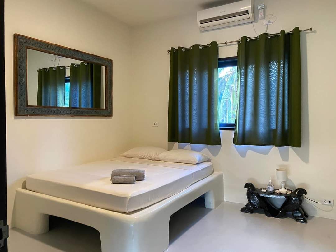 A bedroom with a bed , mirror , curtains and air conditioner.
