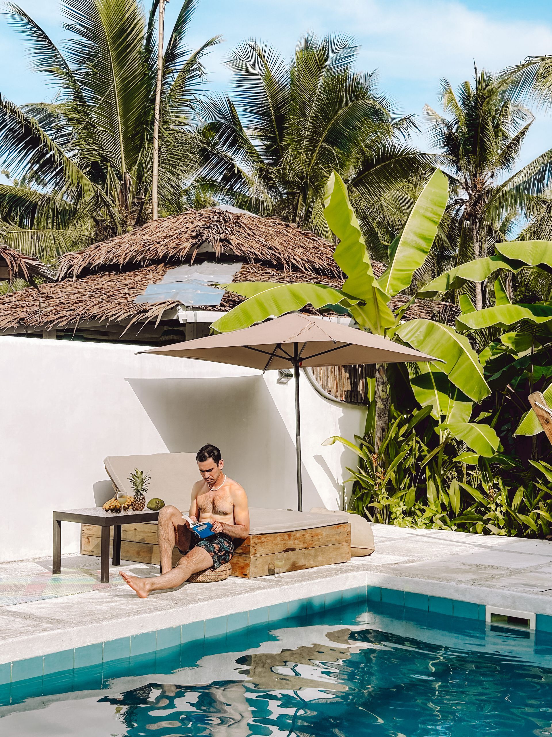 A man is sitting on a bench next to a swimming pool.