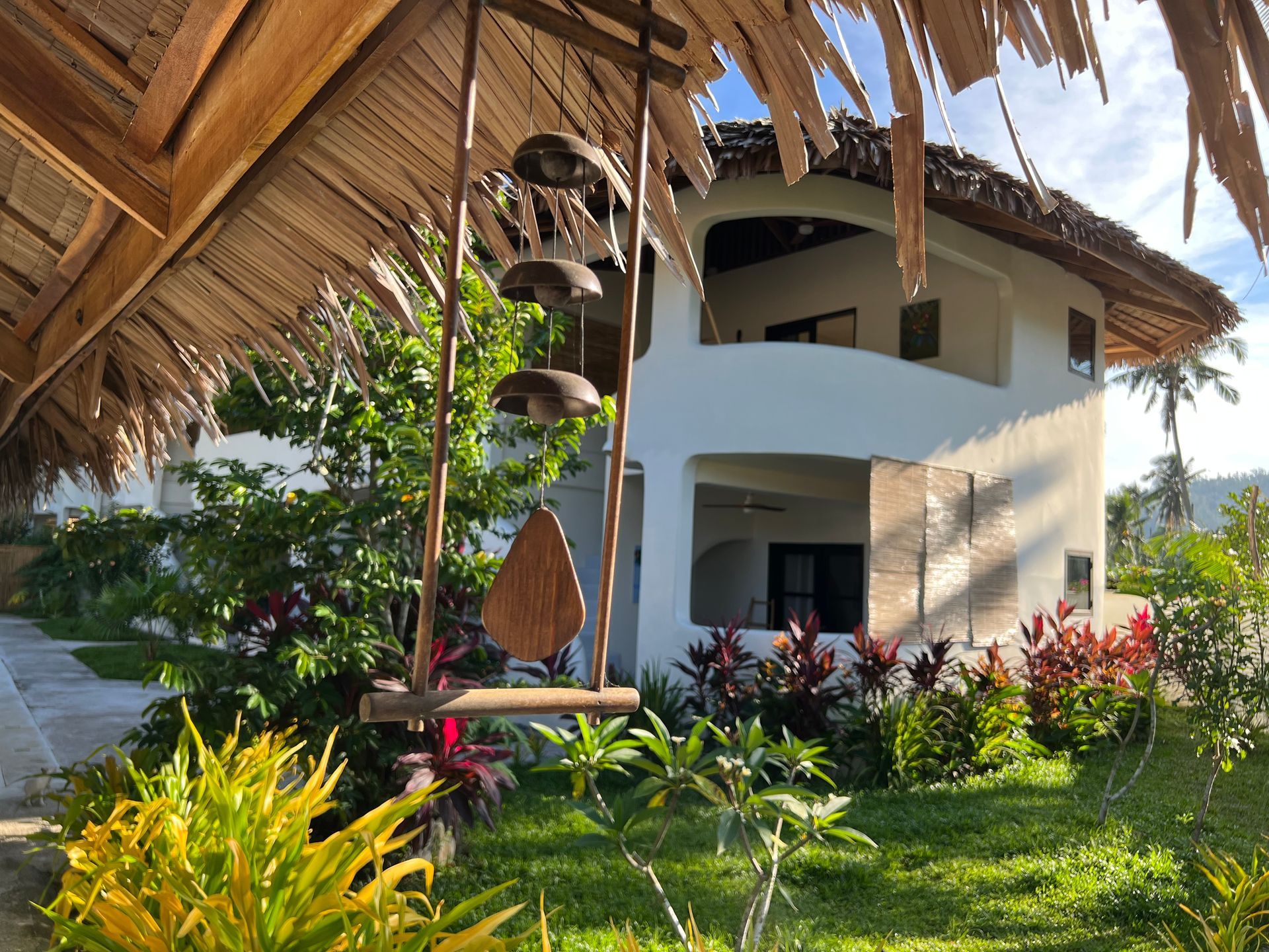 A house with a thatched roof and a swing in front of it