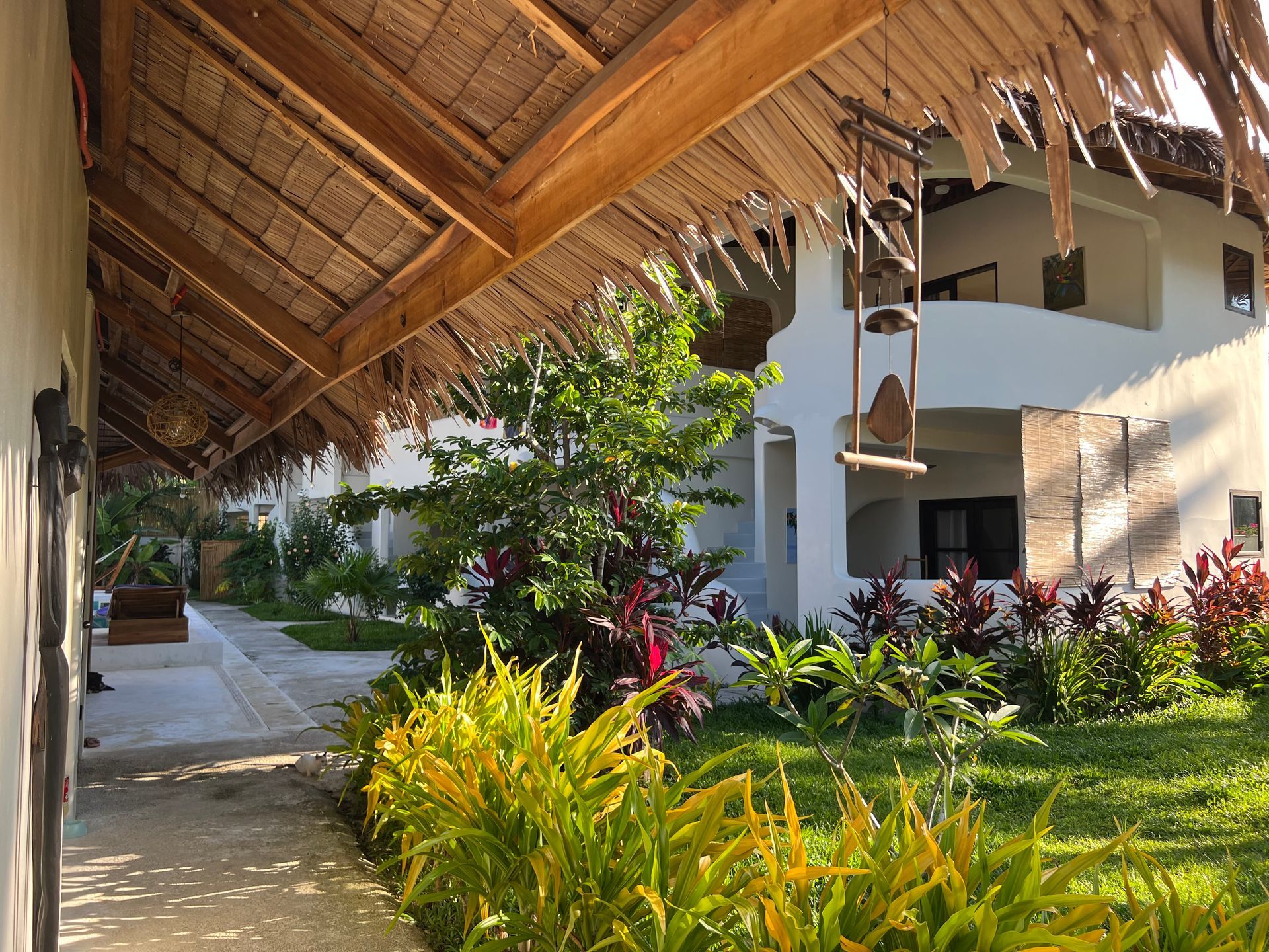 A white building with a thatched roof and a garden in front of it