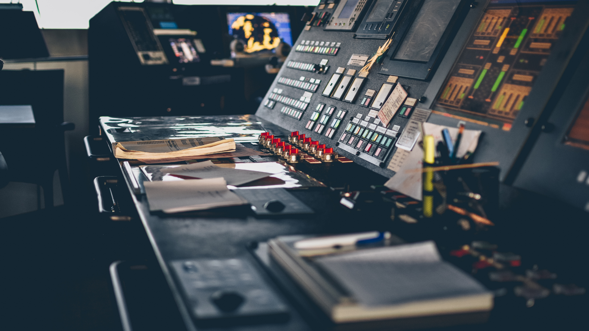 A control room with a lot of buttons and monitors on a table.