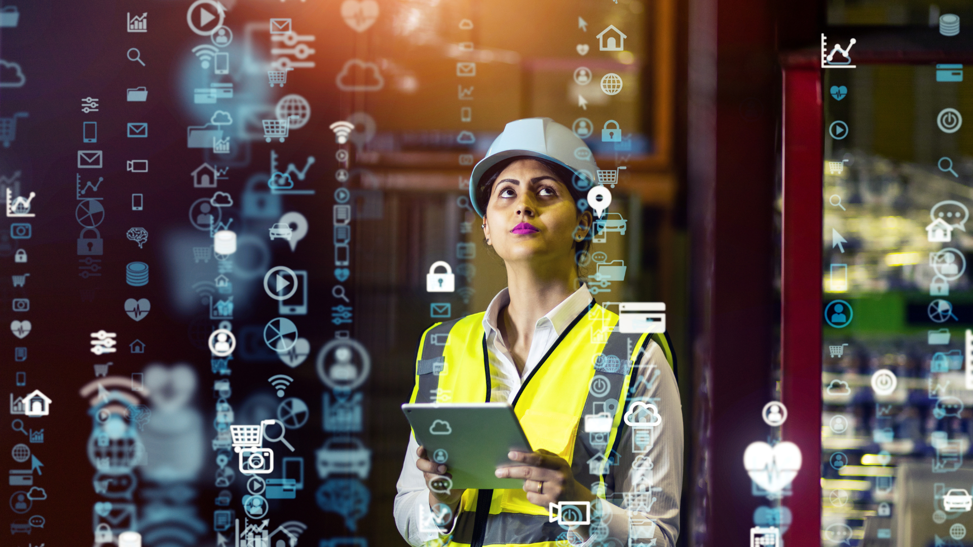 A woman in a hard hat and safety vest is holding a tablet.