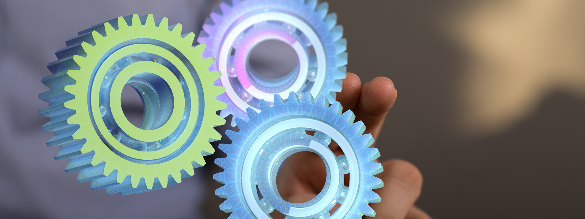 A person is holding three colorful gears in their hand.