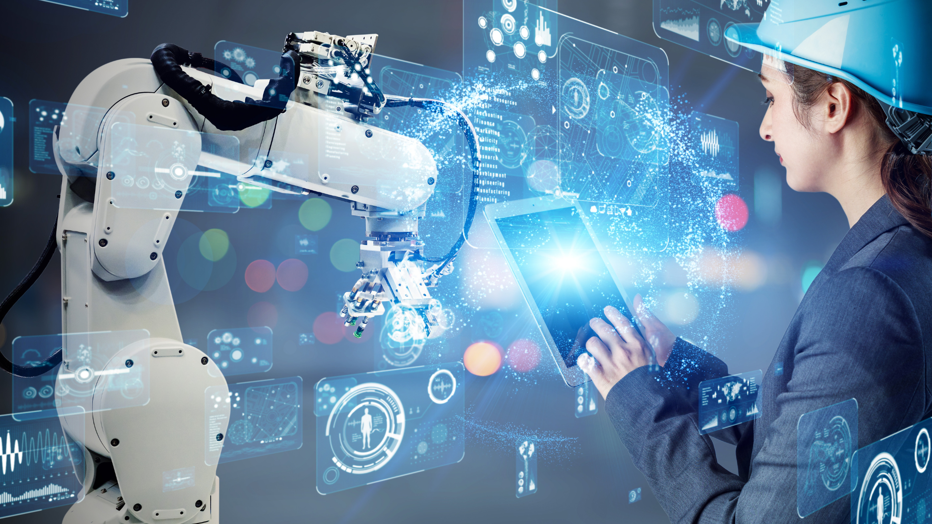 A woman is working on a robot while holding a tablet.