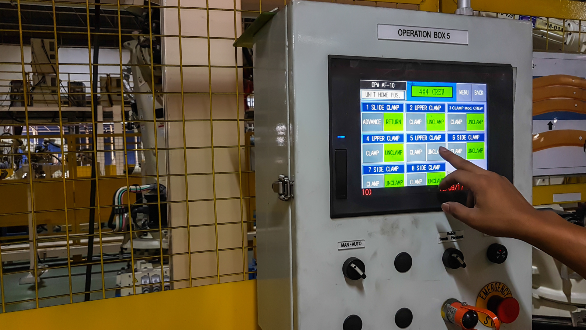 A person is pressing a button on a control panel in a factory.