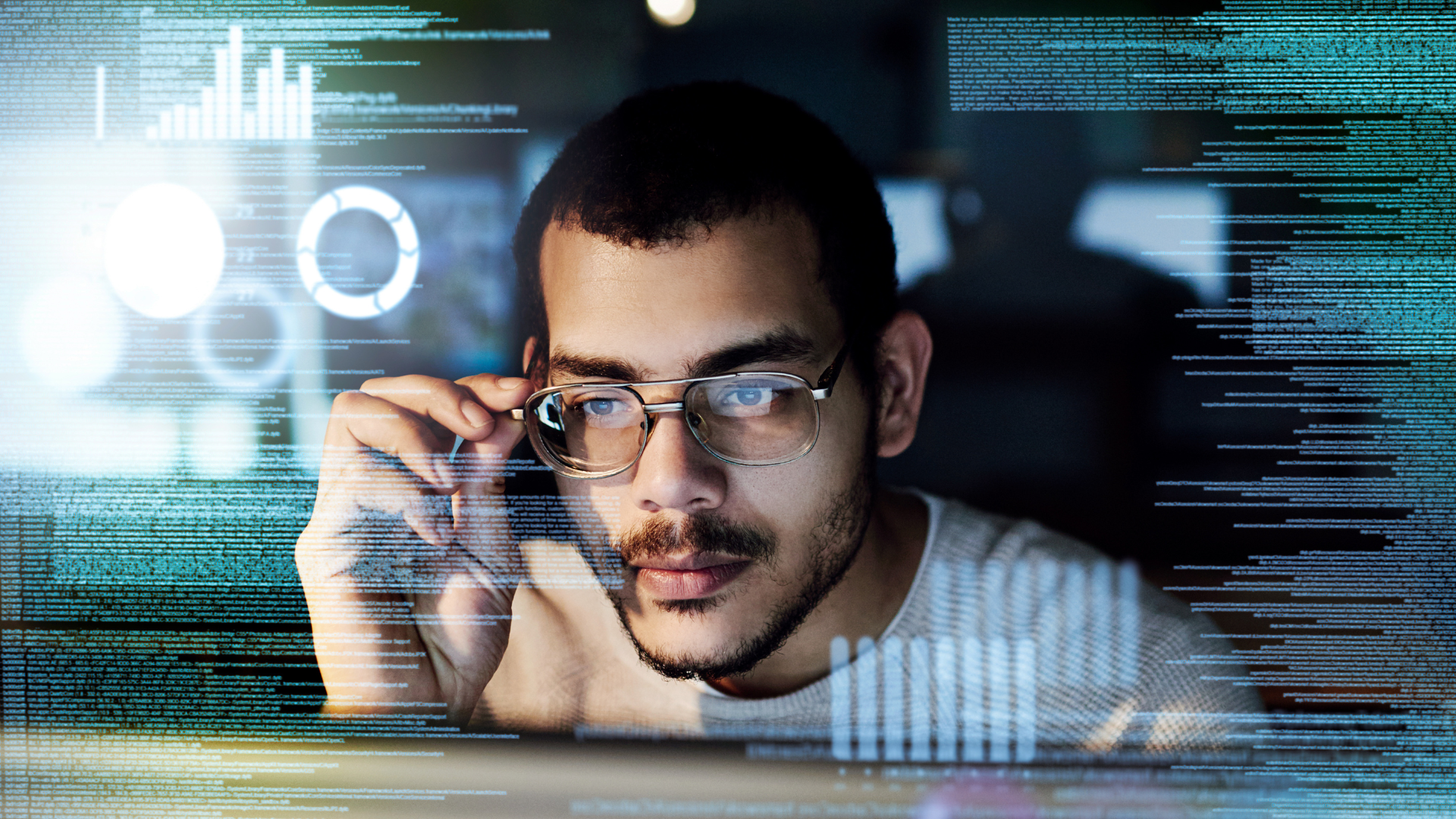 A man wearing glasses is looking at a computer screen.