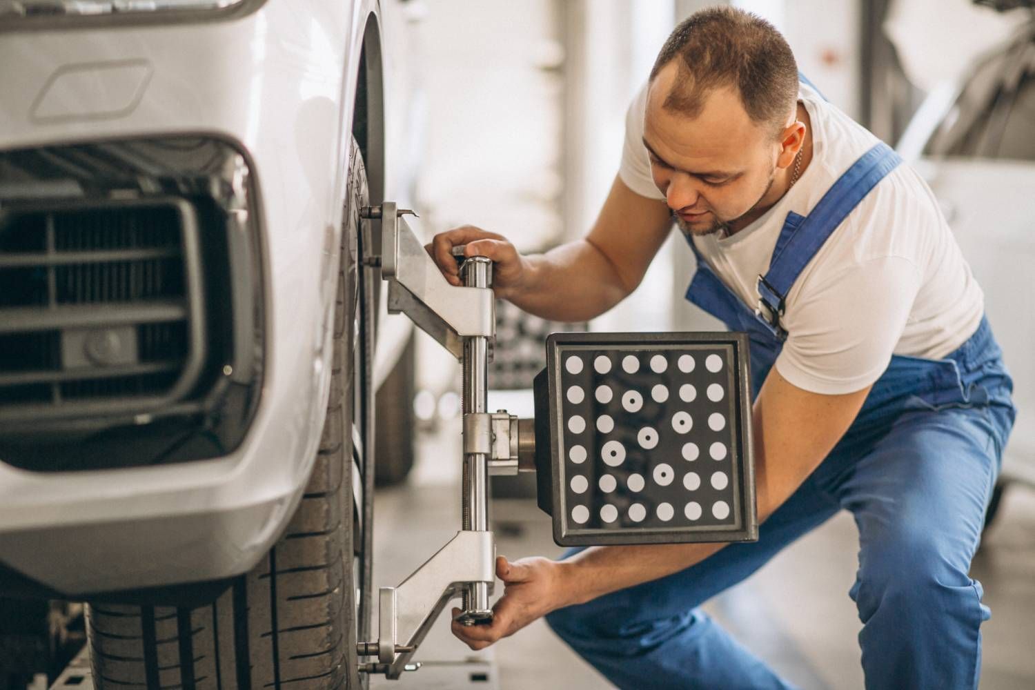 Man in protective gear sanding a car door in a body shop.