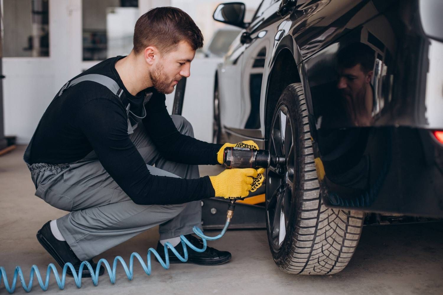 Man in protective gear sanding a car door in a body shop.