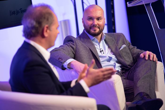 Two men are sitting in chairs talking to each other.