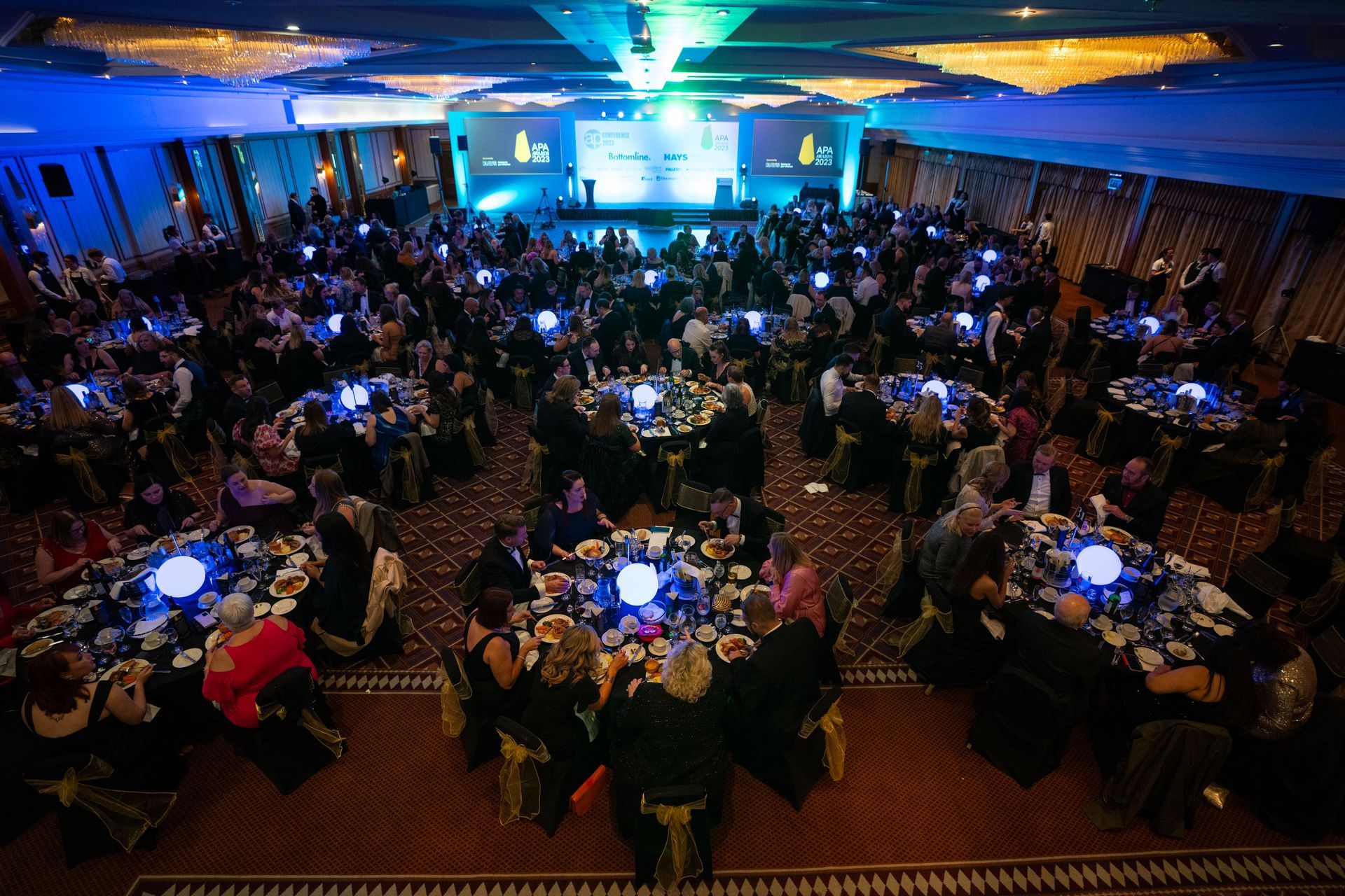 A large room filled with people sitting at tables.