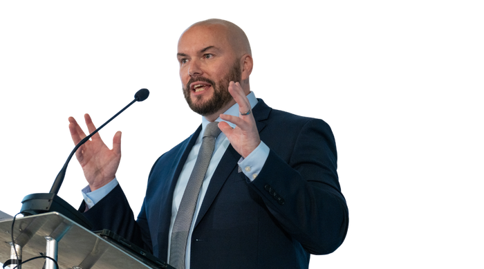 A man in a suit and tie is giving a speech at a podium.