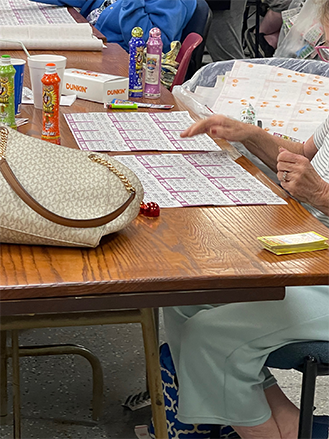 Person playing Bingo on a table with her bing sheet in front of her. 
