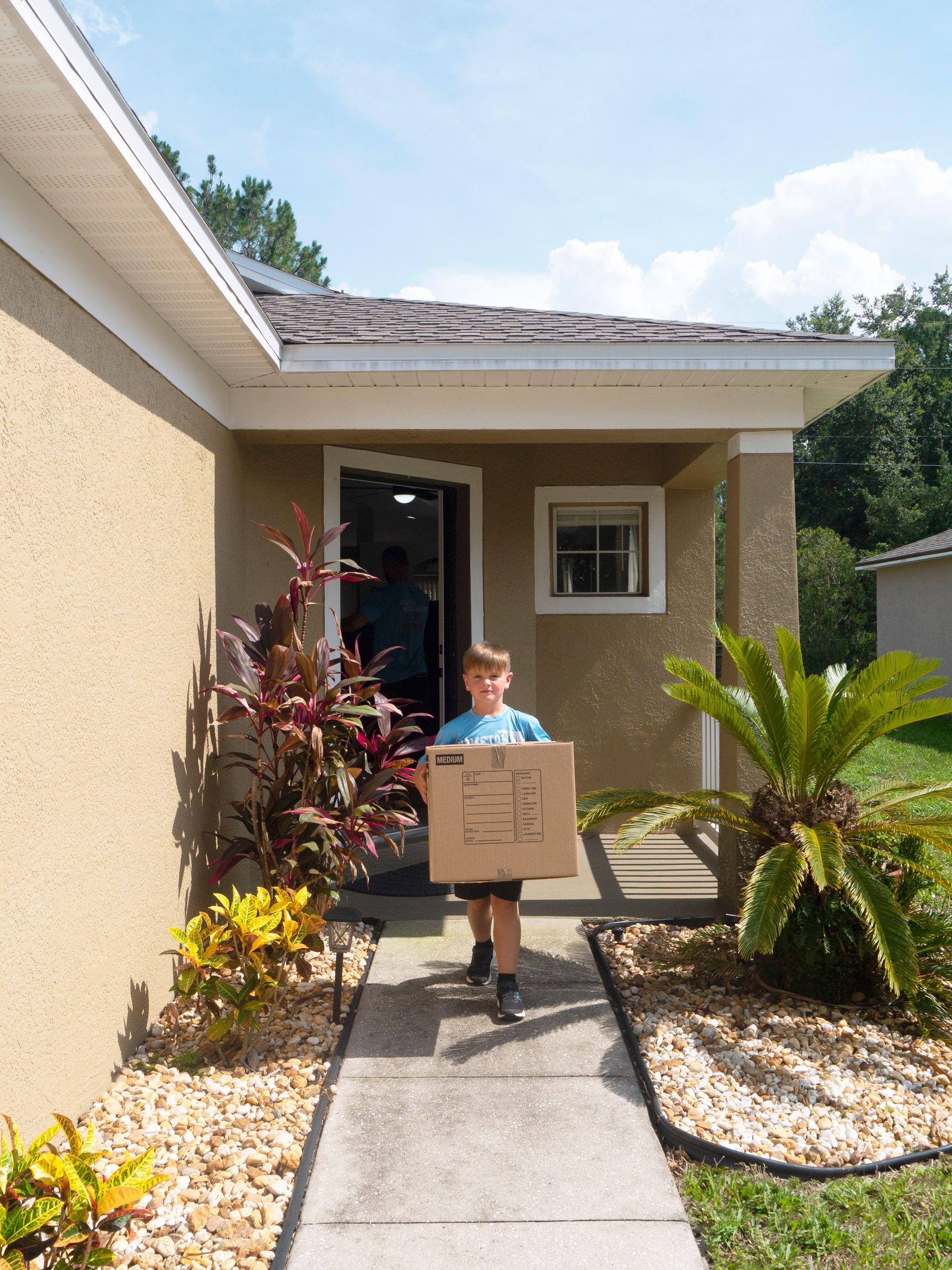 A group of men are carrying boxes into a house.