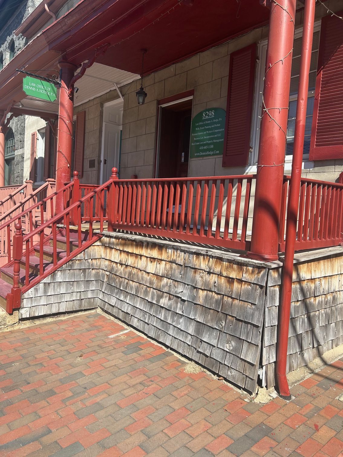 A brick building with a red porch and stairs