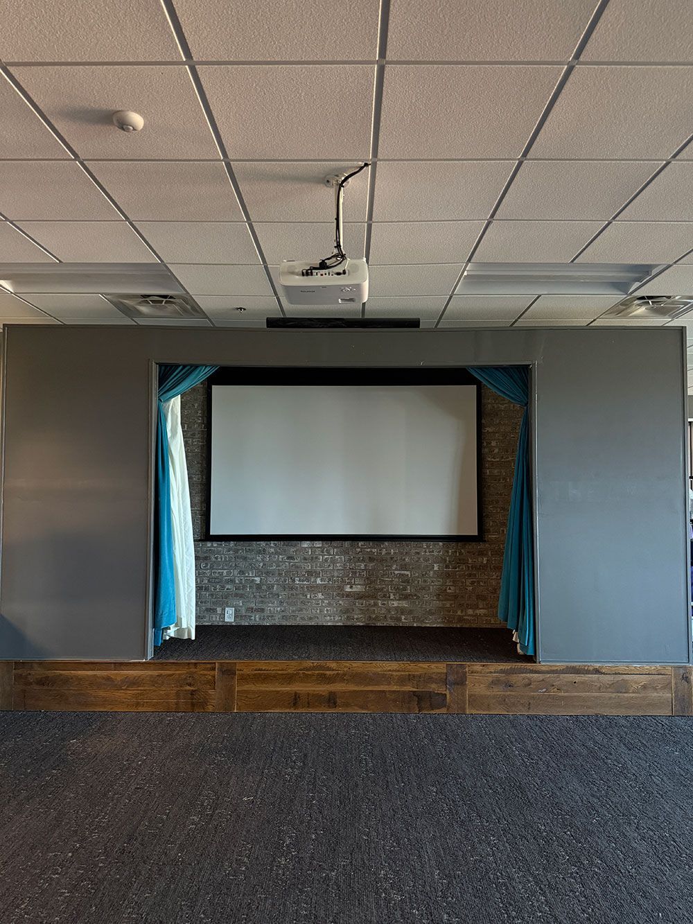 Two people are laying on a couch watching a movie on a projector screen.