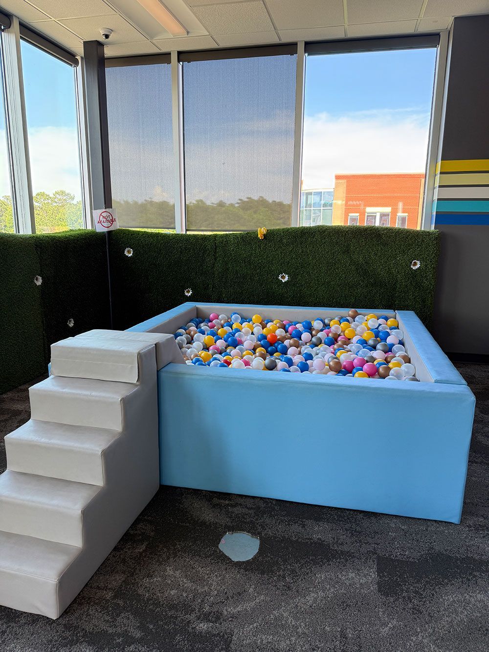 There is a ball pit with stairs in the middle of the room.